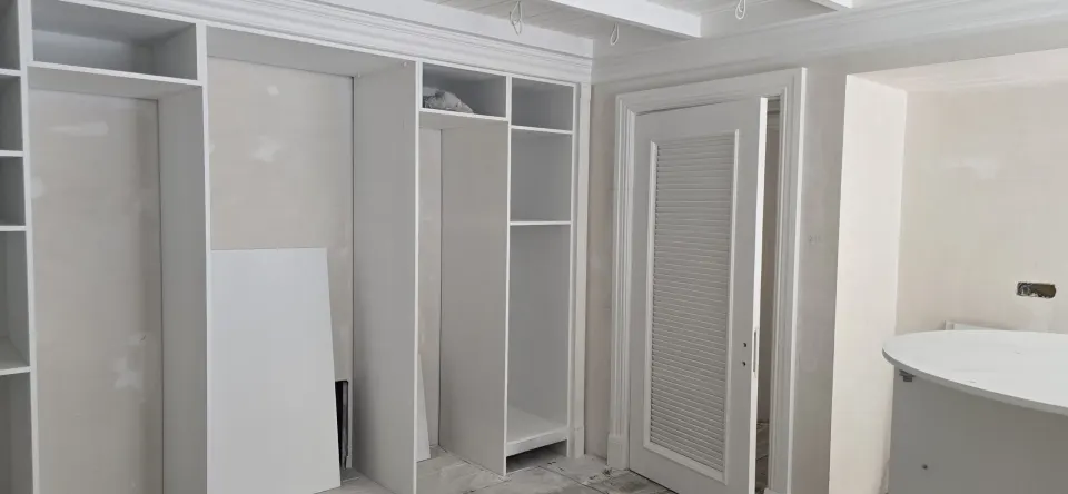 Villa odasında beyaz gömme gardırop gövdeleri ve panjurlu kapı montaj sırasında